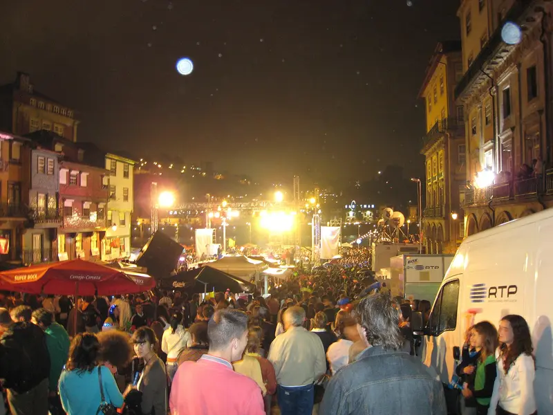 Rua cheia de gente numa noite de arraial, com luzes e barracas