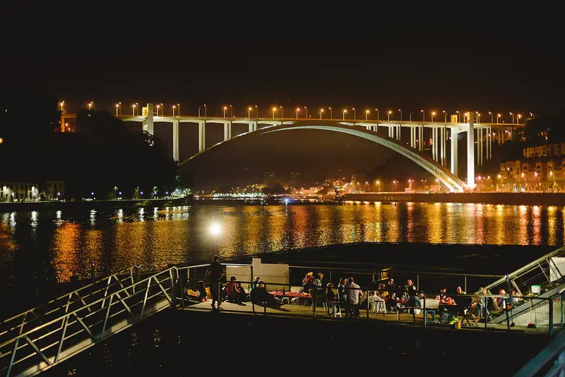 Esplanada junto ao rio numa noite de São João, com a ponte iluminada